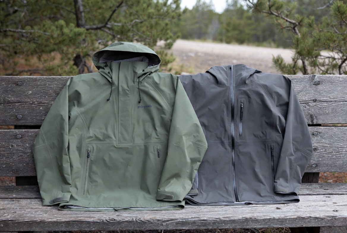 Two rain jackets side-by-side on a wooden bench outdoors, Patagonia Torrentshell in green and Arc'teryx Beta SL in dark gray